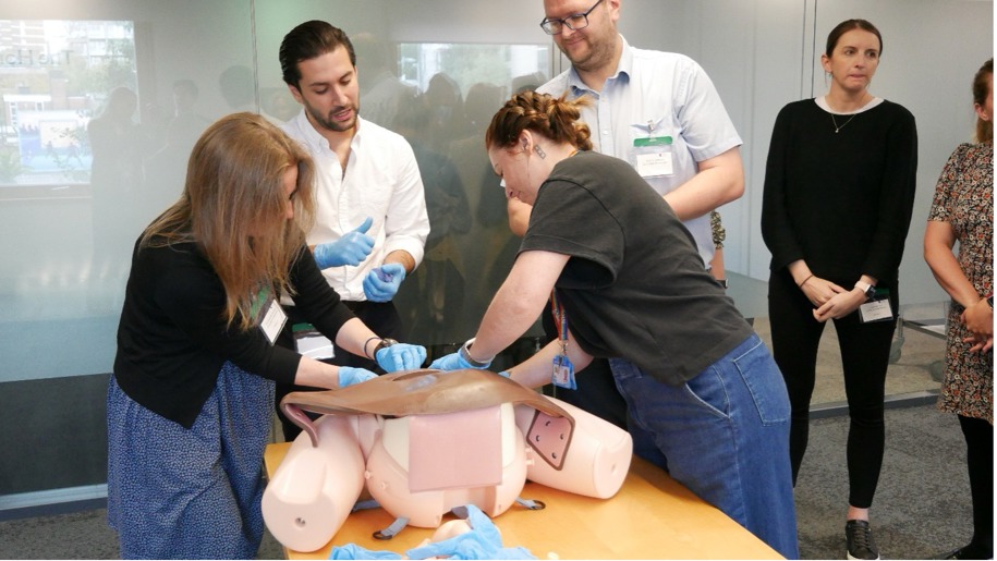 Two women participate in impacted fetal head training using a mannequin